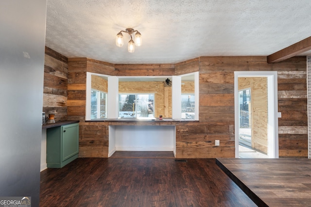 kitchen with wood walls, dark wood-type flooring, green cabinets, and a textured ceiling