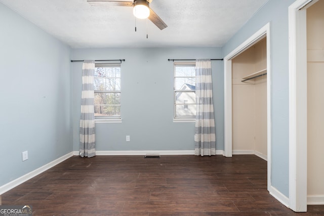 unfurnished bedroom featuring multiple windows, a textured ceiling, baseboards, and wood finished floors