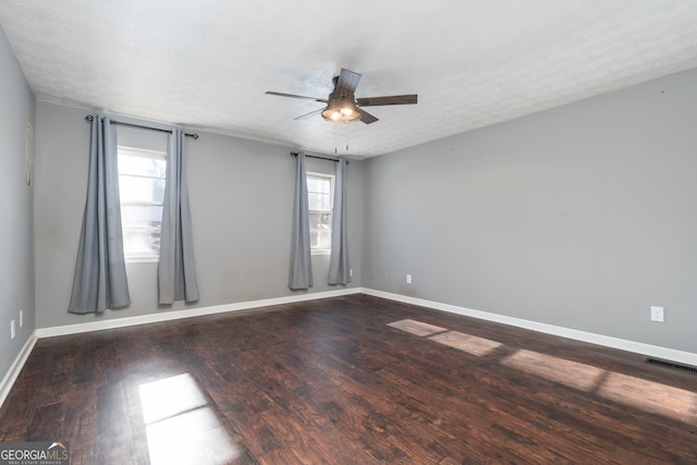 spare room featuring dark wood-style floors, a textured ceiling, and baseboards