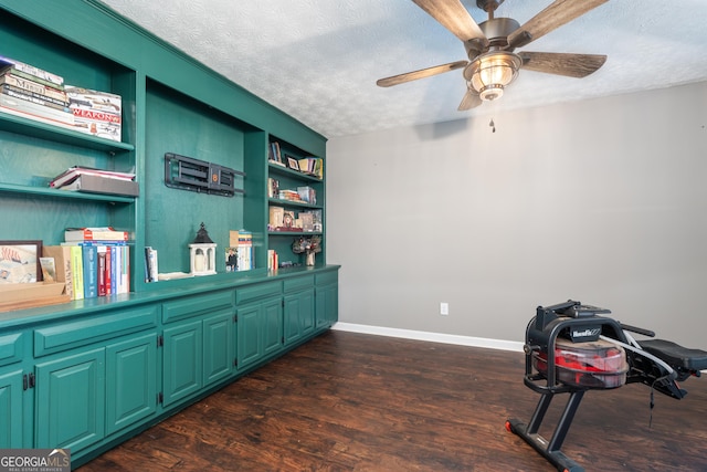 office area with built in features, dark wood-type flooring, a ceiling fan, a textured ceiling, and baseboards