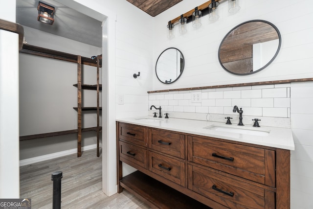 bathroom with double vanity, wood finished floors, a sink, and baseboards