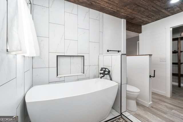 full bath featuring wood finished floors, a freestanding tub, toilet, and tile walls