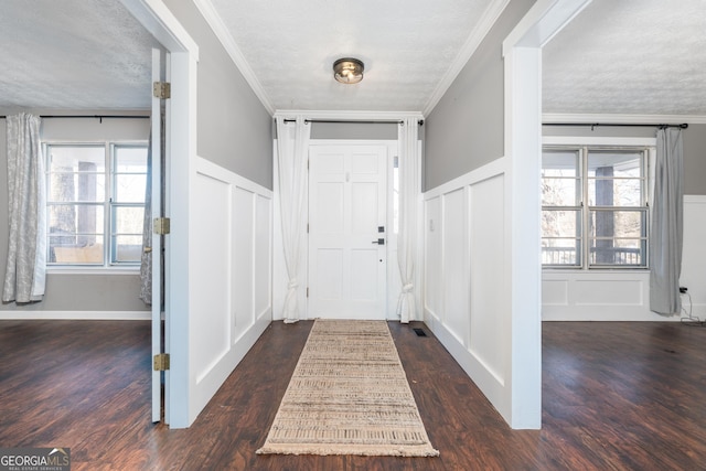 entrance foyer with crown molding, dark wood-type flooring, a textured ceiling, and a decorative wall