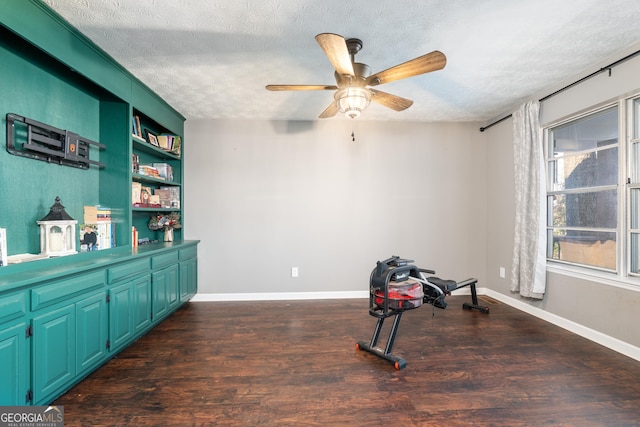 exercise room featuring a textured ceiling, ceiling fan, dark wood-style flooring, and baseboards