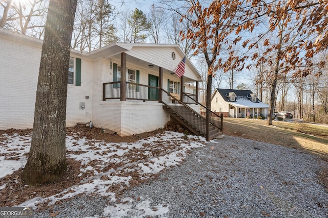 view of front of house with a porch, stairway, and brick siding