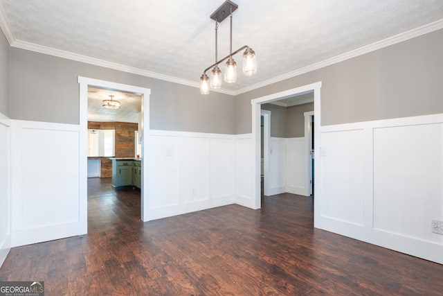 unfurnished dining area featuring a textured ceiling, wainscoting, dark wood finished floors, and crown molding