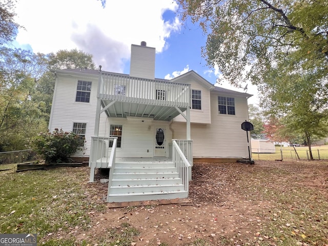 rear view of property with a chimney, fence, and a wooden deck