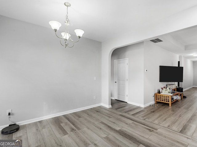 unfurnished dining area featuring arched walkways, wood finished floors, visible vents, and baseboards