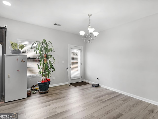 interior space with baseboards, visible vents, a chandelier, and wood finished floors