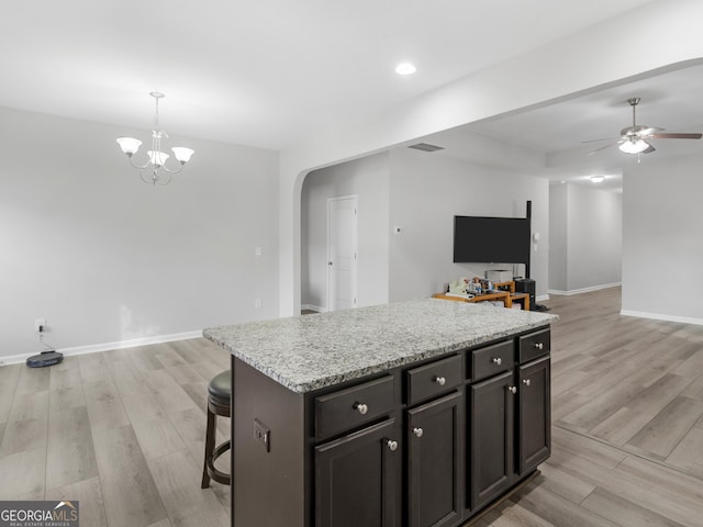 kitchen featuring arched walkways, ceiling fan with notable chandelier, light wood-type flooring, and baseboards