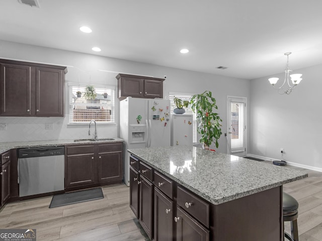 kitchen featuring dishwasher, light stone counters, backsplash, light wood-type flooring, and a sink