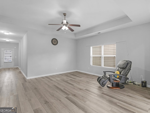 unfurnished room with wood finished floors, a raised ceiling, and baseboards