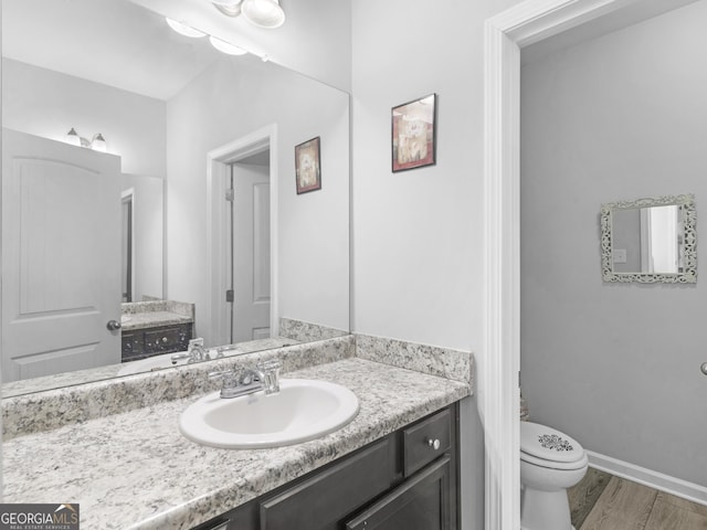 bathroom with vanity, wood finished floors, toilet, and baseboards