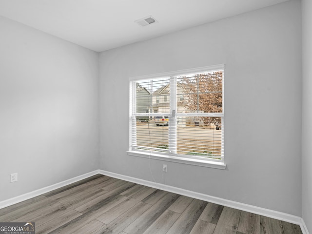 empty room with visible vents, baseboards, and wood finished floors