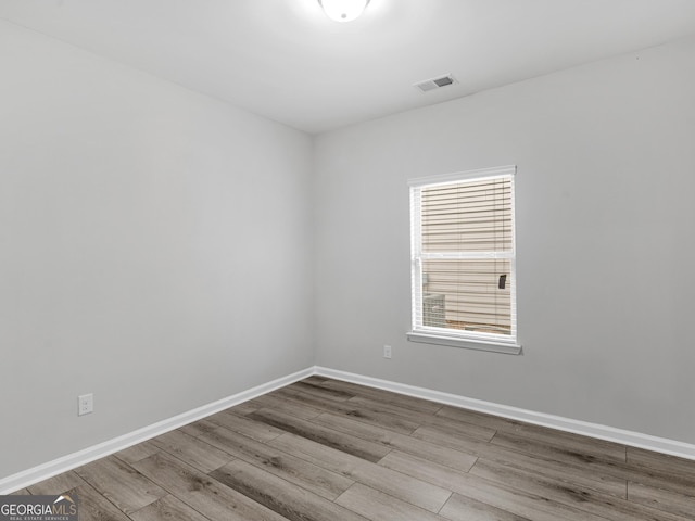 empty room featuring visible vents, baseboards, and wood finished floors