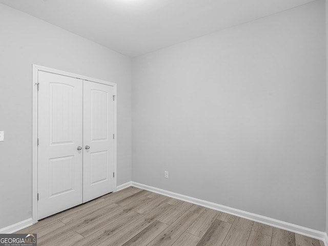 unfurnished bedroom with light wood-style floors, a closet, and baseboards