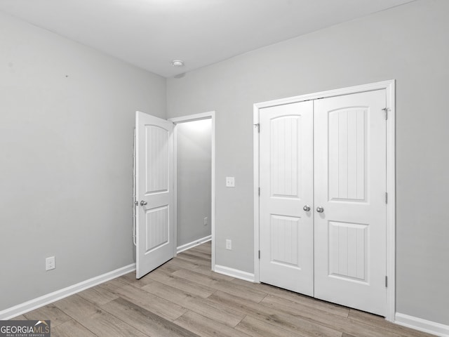 unfurnished bedroom with a closet, baseboards, and light wood finished floors