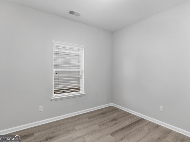 empty room with baseboards, visible vents, and wood finished floors