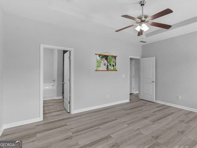 unfurnished bedroom with ensuite bath, wood finished floors, visible vents, and baseboards