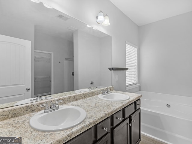 bathroom with a garden tub, visible vents, and a sink