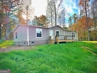 back of property with crawl space, a deck, and a lawn