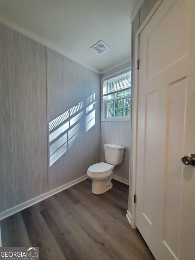 bathroom featuring toilet, wood finished floors, visible vents, and baseboards