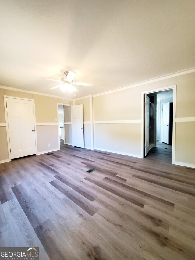 interior space with ornamental molding, a ceiling fan, baseboards, and wood finished floors