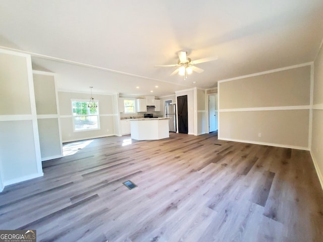 unfurnished living room with visible vents, a ceiling fan, ornamental molding, wood finished floors, and baseboards