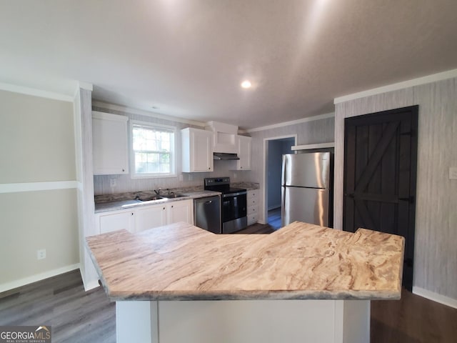 kitchen featuring under cabinet range hood, white cabinetry, stainless steel appliances, and ornamental molding