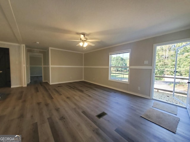 unfurnished living room featuring baseboards, visible vents, ceiling fan, dark wood-style flooring, and crown molding