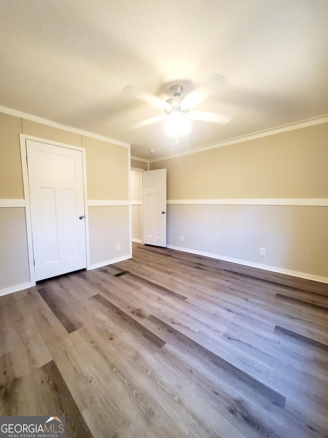 empty room featuring baseboards, ornamental molding, and wood finished floors