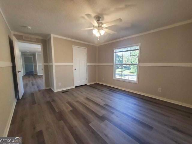 unfurnished bedroom with visible vents, baseboards, dark wood-style flooring, and crown molding