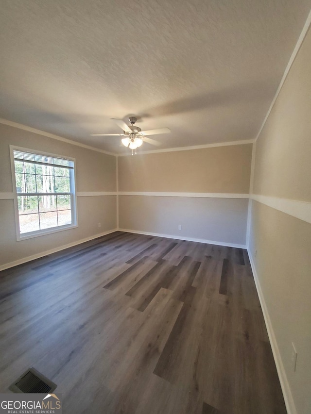 unfurnished room with baseboards, dark wood finished floors, visible vents, and crown molding