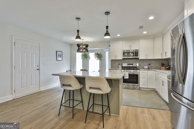 kitchen with tasteful backsplash, appliances with stainless steel finishes, a breakfast bar, light stone counters, and light wood-type flooring