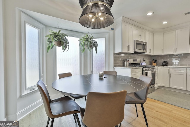 dining space featuring baseboards, plenty of natural light, visible vents, and light wood-style floors