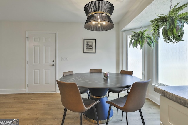 dining space featuring light wood-style flooring and baseboards