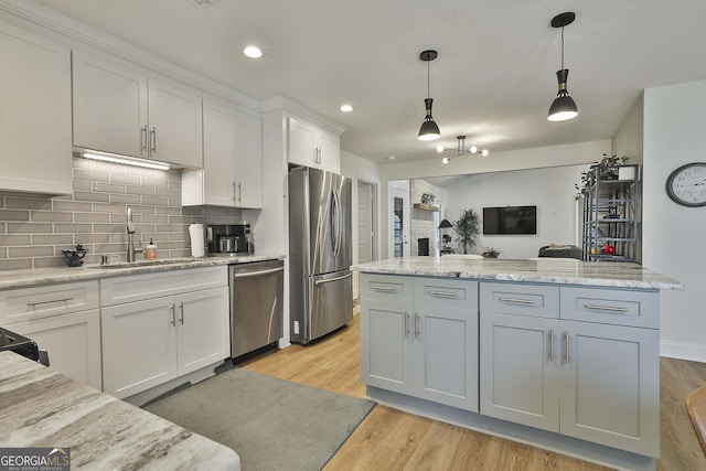 kitchen with stainless steel appliances, white cabinets, a sink, and light wood-style flooring