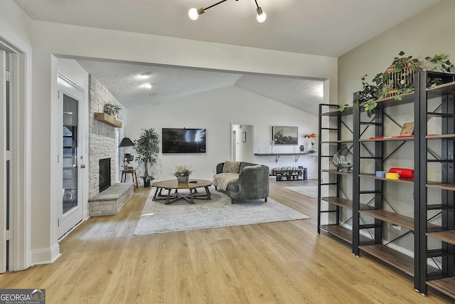 interior space with vaulted ceiling, a fireplace, and wood finished floors