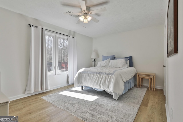 bedroom with light wood-type flooring, a textured ceiling, and baseboards