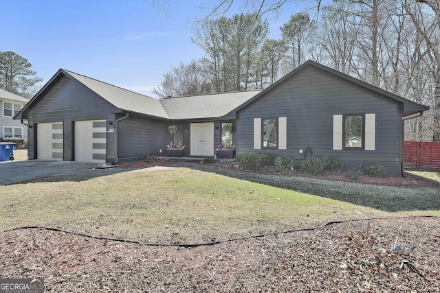 view of front facade with a garage, concrete driveway, a front lawn, and a shingled roof