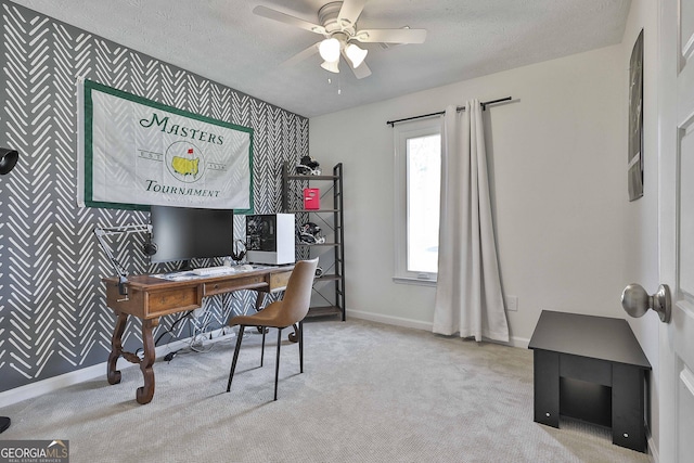 carpeted home office featuring wallpapered walls, an accent wall, baseboards, and a textured ceiling