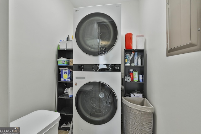 clothes washing area featuring stacked washer and clothes dryer, electric panel, and laundry area