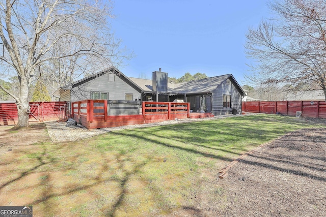 back of house with a chimney, fence, and a lawn