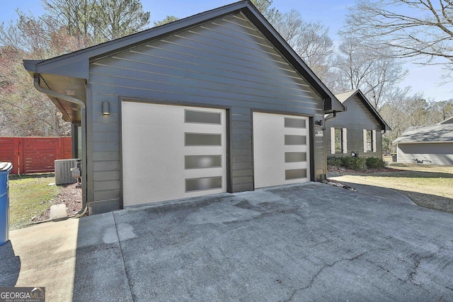 detached garage featuring fence and central AC unit