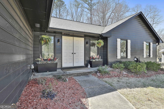 property entrance featuring a shingled roof