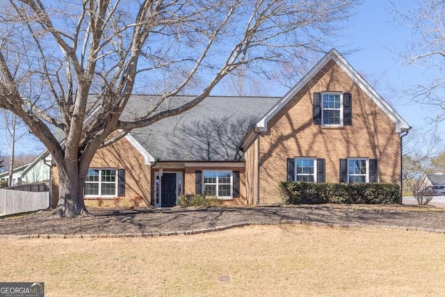 view of front of property with roof with shingles, fence, and brick siding