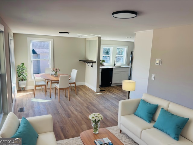 living room featuring baseboards, visible vents, and wood finished floors