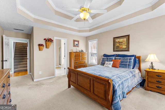 bedroom featuring a tray ceiling, light colored carpet, visible vents, ornamental molding, and baseboards