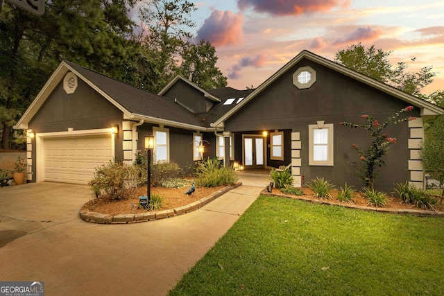 view of front facade with a garage, french doors, concrete driveway, and stucco siding