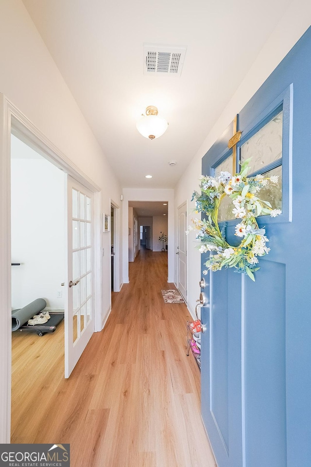 hallway with french doors, light wood-style flooring, and visible vents